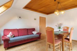 a living room with a red couch and a table at Sulzerhof in Bad Rippoldsau-Schapbach