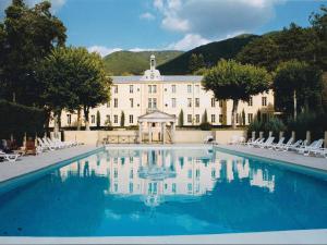 a large building with a swimming pool in front of it at Appartement Duplex Rez Jardin in Montbrun-les-Bains