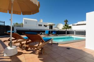 para krzeseł i parasol obok basenu w obiekcie Grand Villa Famara Puerto del Carmen w Puerto del Carmen