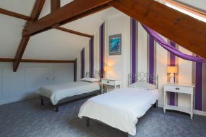 two beds in a room with purple curtains at Gite les coquelicots Proche mer in Paimpol