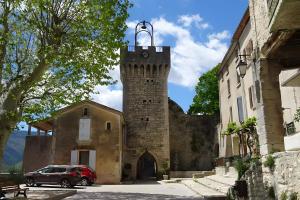 a building with a tower with a car parked in front at Appartement Duplex Rez Jardin in Montbrun-les-Bains