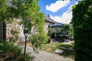a garden with a wooden deck with a table and chairs at Gite les coquelicots Proche mer in Paimpol