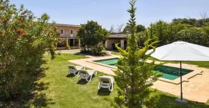 a backyard with a swimming pool with chairs and an umbrella at Cadernera in Búger