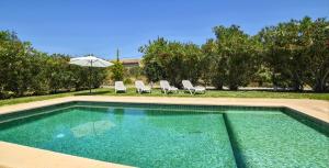 a swimming pool with two chairs and an umbrella at Cadernera in Búger
