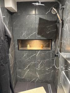 a black tiled shower with a shelf in a bathroom at T2 modern in Frontenex-Villard-Rosset