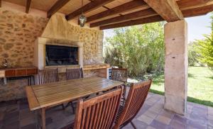 an outdoor patio with a wooden table and a fireplace at Cadernera in Búger