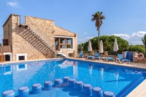a swimming pool with chairs and a house at Finca Can Jeroni in Felanitx