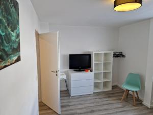 a living room with a television and a chair at Wohnung Barbarossa in Rommelhausen