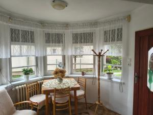 a dining room with a table and chairs and windows at Vidiecky Dom in Mojmírovce