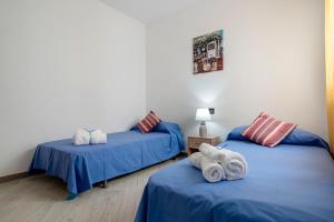 two beds in a room with blue sheets and towels at Cambrils Turistic 3b in Cambrils