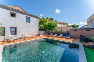 a swimming pool with chairs and a house at Côté Cour in Rasteau