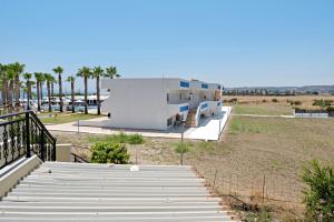 a building on the beach with palm trees in the background at Athina seaside in Kardamaina