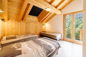 two beds in a room with wooden walls and windows at Lamartine in Valloire