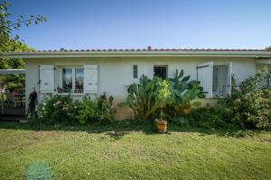 a white house with plants in front of it at Maison agréable et tranquille in Gujan-Mestras