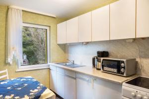 a kitchen with white cabinets and a microwave at Haus am Candelaber in Altenbergen +17 photos
