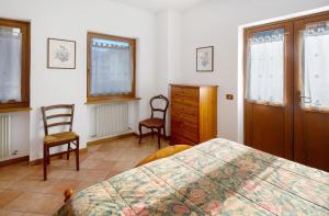 a bedroom with a bed and two chairs and a dresser at Residence Malibu Appartamento 4 in Falcade