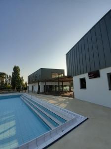 a swimming pool in front of a building at Camping Arquebuse in Auxonne