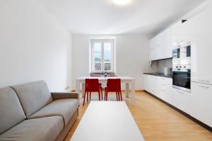 a living room with a couch and a table with red chairs at Greta House in Colico