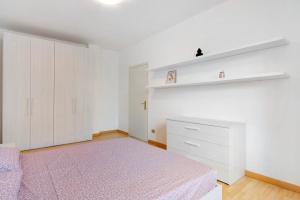 a white bedroom with a bed and a shelf at Greta House in Colico