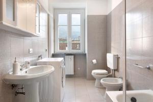 a white bathroom with a sink and a toilet at Greta House in Colico