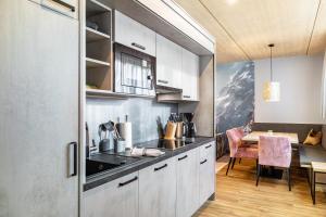 a kitchen with white cabinets and a dining table at Apartment Steinbock in Pflach