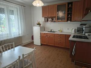 a kitchen with wooden cabinets and a white refrigerator at Vidiecky Dom in Mojmírovce +12 photos