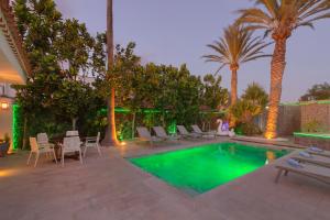 a pool with chairs and a table and palm trees at Villa Ginevra in Arona