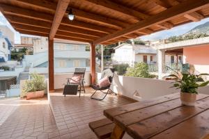 a patio with a wooden table and chairs on a balcony at Holiday vista Montagna in Cala Gonone