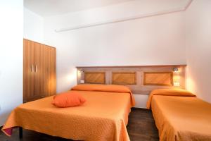 two beds in a room with orange sheets at Holiday vista Montagna in Cala Gonone
