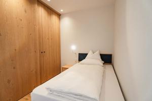 a bedroom with a white bed and a wooden cabinet at Valentinerhof Apt Aqua in San Michele
