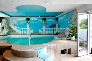 a room with a swimming pool with palm trees on the wall at Wellness Ferienwohnung Müller in Rostock