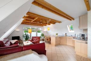 a living room with a red couch and a kitchen at Wellness Ferienwohnung Müller in Rostock