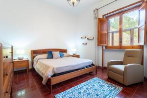 a bedroom with a bed and a chair and a window at Villa Serra in Marina Serra