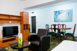 ein Wohnzimmer mit Tisch, Stühlen und Fernseher in der Unterkunft West Gate Studios in Bukarest