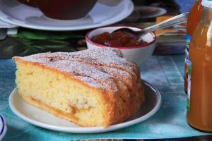 a piece of cake on a plate with a bowl of jam at Bed and Breakfast Torrette Etrusche in Capalbio