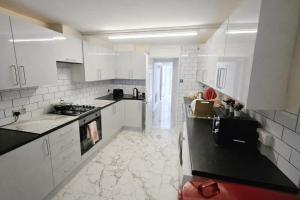 a kitchen with white cabinets and black counter tops at ValueStays Chalvey Free Parking in Slough