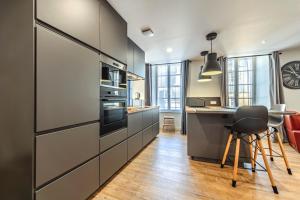 a kitchen with gray cabinets and a table and a stool at Appartement du Théâtre Morlaix in Morlaix