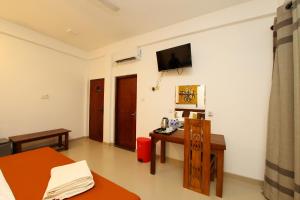 a room with a desk and a tv on the wall at Hotel Emerald Green in Weligama