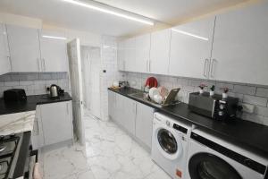 a kitchen with white cabinets and a washing machine at ValueStays Chalvey Free Parking in Slough +33 photos