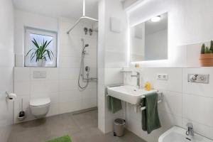 a white bathroom with a sink and a toilet at Ferienwohnung am Klemmbach in Müllheim +15 photos