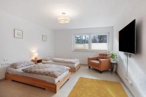 a bedroom with two beds and a tv and a chair at Ferienwohnung am Klemmbach in Müllheim