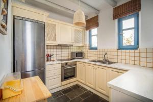 a kitchen with white cabinets and a stainless steel refrigerator at Almira in Livadi +4 photos
