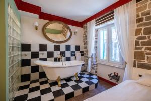a bathroom with a tub and a checkerboard floor at Casa Libertà Suites & Studios Piran in Piran +85 photos