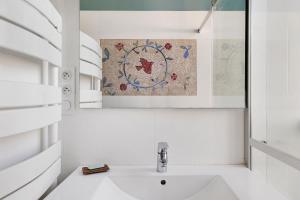 a white bathroom with a sink and a mosaic on the wall at Quartier De La Madeleine in Angers +16 photos