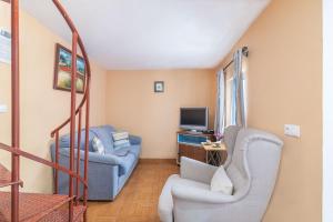 a living room with two chairs and a television at Casa das Bonecas in Farelos de Baixo