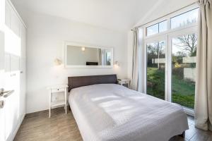 a white bedroom with a bed and a window at Sonnenuferhaus in Kosel