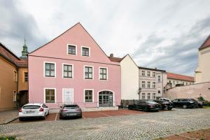 a pink building with cars parked in a parking lot at Luckau Appartements 1695 in Luckau