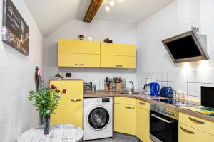 a kitchen with yellow cabinets and a washer and dryer at Ferienwohnung Thüringer Wald in Ilmenau