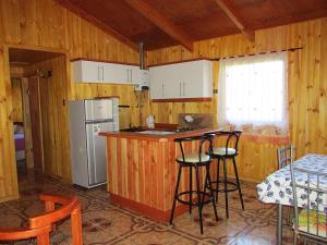 a kitchen with a counter and two bar stools at Cabañas Entremontañas Coñaripe in Coñaripe
