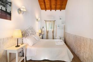 a white bedroom with a white bed and a lamp at Quinta do Mestre - Casa Do Mar in Tavira